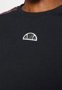 Zwarte sweatshirt met een rond logo met witte randen op de borst. Ribbelkraag en roze accent op de schoudernaden.