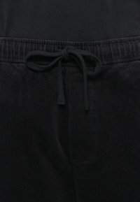 Schwarze Cordhosen mit strukturiertem Finish, elastischem Bund und Kordelzug vorne.