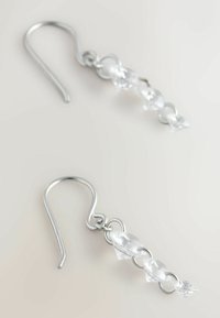 Hõbedast traadist konks-kõrvarõngad, millel on selged, lihvitud kristallaktsendid pikendatud kujul, ühendatud ümmarguste metallkettidega.