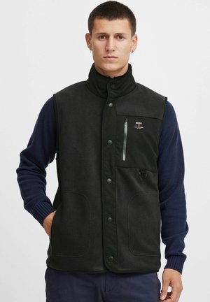 Black fleece vest with a high collar, snap closure, two front pockets, and a zippered chest pocket. Features a small logo on the chest.