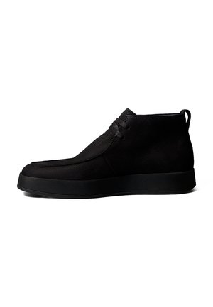 Schwarzer Leder-Mid-Top-Freizeitschuh mit Schnürverschluss und flacher Gummisohle vor weißem Hintergrund.