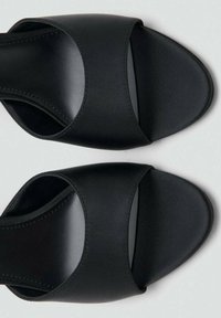 Sandalias tipo slide negras hechas de cuero sintético, con punta abierta, tiras anchas y una textura suave con detalles mínimos de costura.