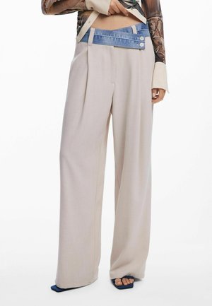 Beige wijde broek met een opvallende denim tailleband met twee knopen. Soepele textuur, ruime pasvorm en subtiele plooien in de stof.