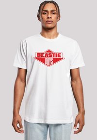 White cotton t-shirt featuring a large red "BEASTIE BOYS" logo in a diamond shape. Short sleeves and a crew neck design.