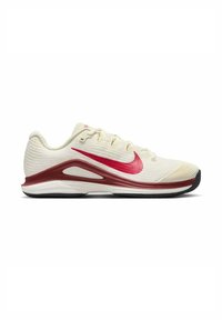 Scarpa sportiva di un beige chiaro con una texture rigata, logo Swoosh rosso e dettagli marrone scuro sulla suola intermedia. Presenta una suola in gomma nera.