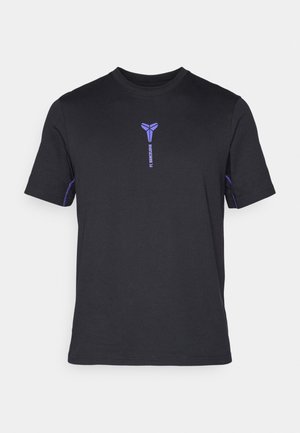 Schwarzes T-Shirt aus Baumwolle mit einem kleinen lila FC Barcelona-Logo auf der Vorderseite und lila Akzenten an den Ärmeln. Rundhalsausschnitt.