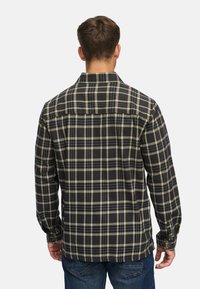 Ternede flannel skjorte med et mønster i sort, grøn og blå. Lange ærmer, knapkrave og bølget kant. Blødt bomuldsstof.