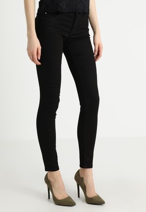 Zwarte skinny jeans gemaakt van stretch denim, met een klassiek vijf-pocket ontwerp, gecombineerd met olijfgroene high heels.