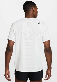 Λευκό αθλητικό t-shirt με κοντά μανίκια, με διάτρητη υφή και μαύρο λογότυπο Nike στον ώμο. Κατασκευασμένο από διαπνέον υλικό.