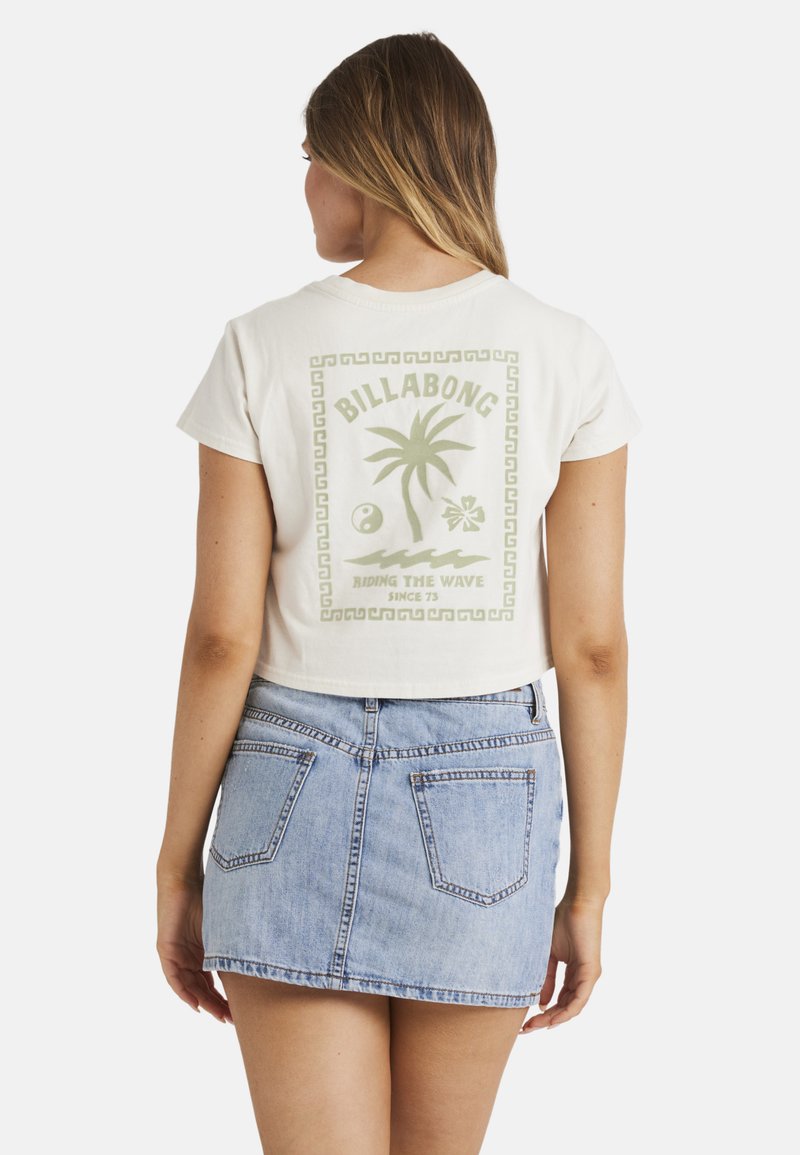 Cremefarvet cropped t-shirt med et grønt grafisk design af palmer og tekst. Sammen med en lys blå denimskørt med baglommer.