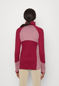 Långärmad pullover i burgundy och ljusrosa nyanser, med hög krage, raglanärmar och en mjuk yta.