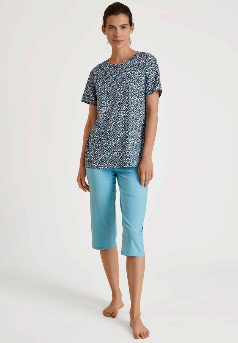 Korte mouwen blauwe gebloemde top gecombineerd met lichtblauwe cropped broek. Glad materiaal, comfortabele pasvorm, geometrisch ontwerp op het shirt.