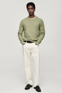 Grüner Strickpullover, kremfarbene Hose, schwarzer Gürtel und schwarze Schuhe. Der Pullover hat einen Rundhalsausschnitt, und die Hose ist im straight-leg Stil mit einer glatten Textur.
