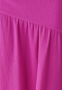 Bright pink fabric with a textured surface, featuring gathers on one side for a stylish, flowing appearance.
