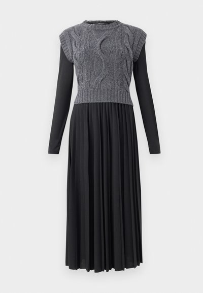 Sweater dress with gray cable-knit bodice and black pleated skirt. Features short sleeves and a round neckline. Long flowing design.