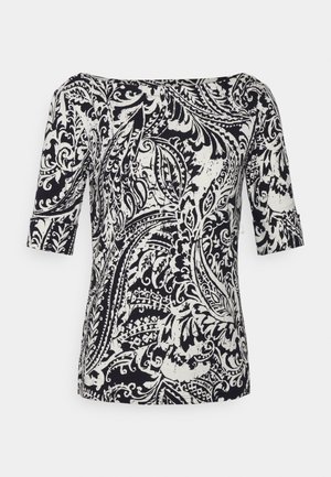 Blouse à manches courtes à motif cachemire noir et blanc avec un décolleté bateau, présentée sur un fond neutre.