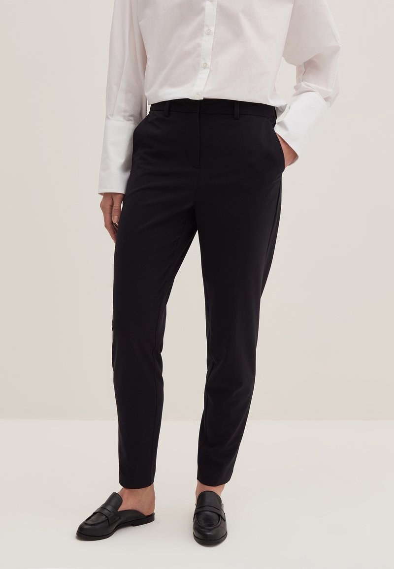 Černé kalhoty na míru se slim fit střihem, vyrobené z hladkého materiálu, s bočními kapsami a plochým designem vpředu, doplněné o černé mokasíny.