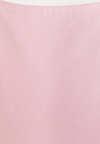 Tejido rosa claro con una suave textura acanalada, que presenta un borde liso y un sutil detalle de costura a lo largo de la parte superior.