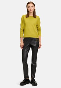Maglione lavorato a maglia verde lime con maniche lunghe, abbinato a pantaloni in finta pelle nera a vita alta e scarpe nere con plateau.