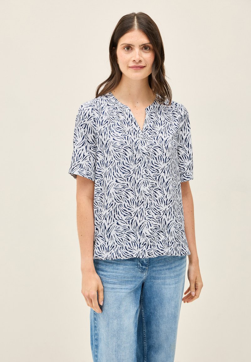 Blusa leggera bianca con motivo foglia navy, maniche corte e scollo a V. Realizzata in un tessuto morbido e traspirante.