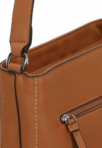 Sac à main en cuir tan au design structuré, avec une poche zippée, des accessoires en argent et des coutures contrastantes le long des bords.