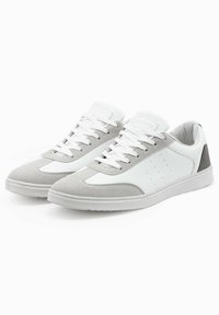 Graue und weiße Sneakers aus Wildleder und Leder, mit einer runden Zehenpartie, weißen Schnürsenkeln, durchbrochenen Akzenten und einem strukturierten Fersenbereich.