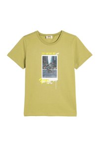 Camiseta de manga corta de color verde oliva hecha de algodón. Presenta un estampado gráfico con texto y una foto de un patinador en la parte frontal.