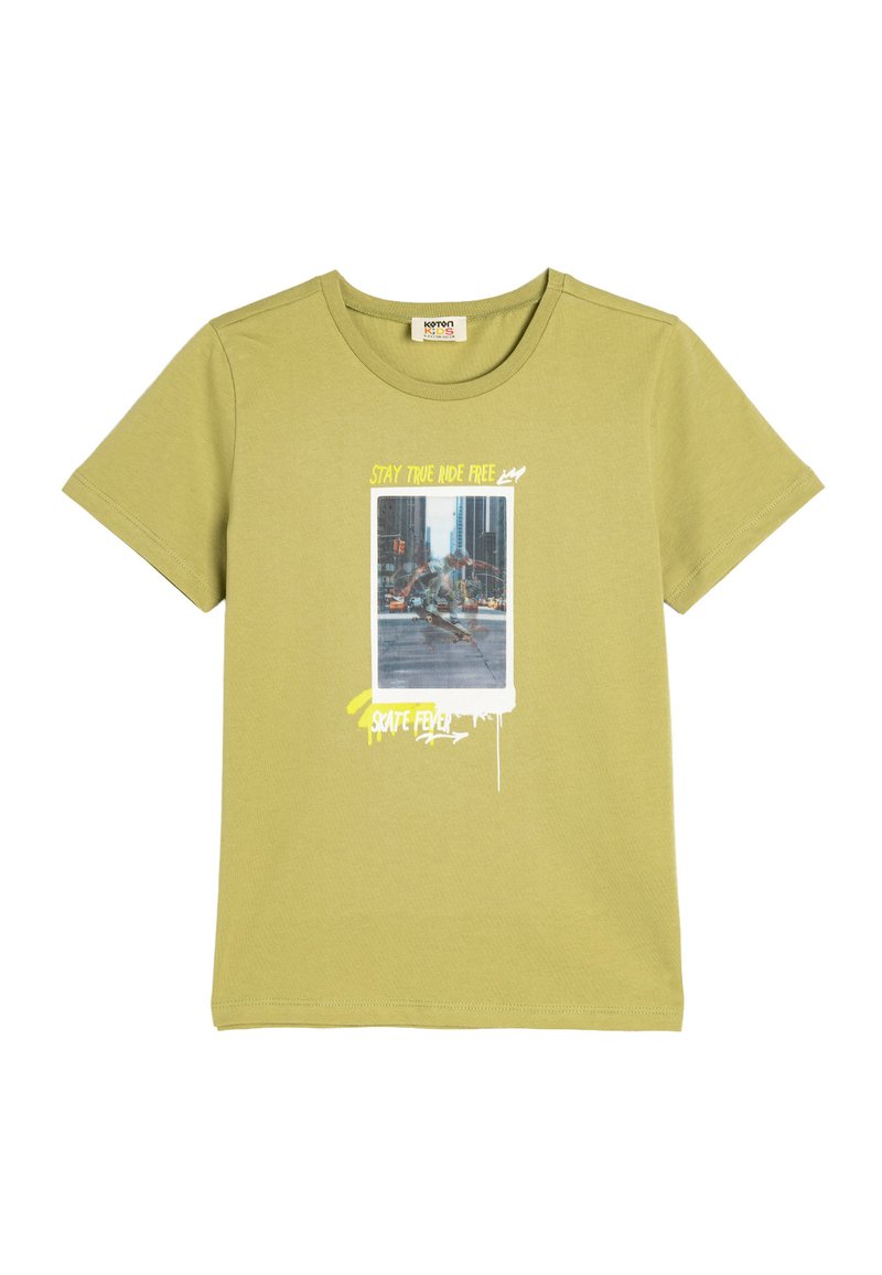 Camiseta de manga corta de color verde oliva hecha de algodón. Presenta un estampado gráfico con texto y una foto de un patinador en la parte frontal.