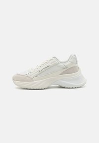Sneaker bianca realizzata in materiali lisci e testurizzati, con una suola spessa, punta arrotondata e un branding discreto sul lato.