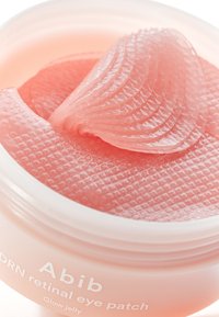 Patch oculaire rétinien Abib dans un récipient rond blanc. Patches translucides roses, semblables à de la gelée, avec une surface texturée disposés à l'intérieur.