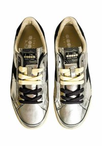 Zilverkleurige leren sneakers met zwarte accenten, voorzien van een gestructureerde afwerking, beige en zwarte veters, en een gelabelde binnenzool met geometrisch ontwerp.