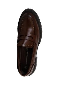 Mocassino in pelle marrone con decorazioni in metallo, dettagli a fiocco sulla fascia e suola in gomma spessa per maggiore aderenza e comfort.