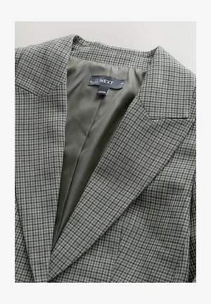 Šedé kárované sako s ostrými klopami, vybavené hladkou olivově zelenou podšívkou a štítkem označeným "NEXT" uvnitř límce.