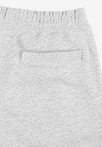 Szare dresy z elastycznym paskiem w talii i płaską tylną kieszenią. Materiał jest miękki z delikatną teksturą. Prosty, minimalistyczny design.