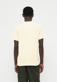 Φωτεινό κίτρινο κοντομάνικο μπλουζάκι από βαμβάκι, με κλασικό στρογγυλό λαιμό και άνετη εφαρμογή, με λεία υφή και καθαρές άκρες.