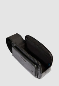 Borsa a tracolla in pelle nera con chiusura zip, dotata di tasche interne e una texture liscia. Design elegante con dettagli brandizzati.