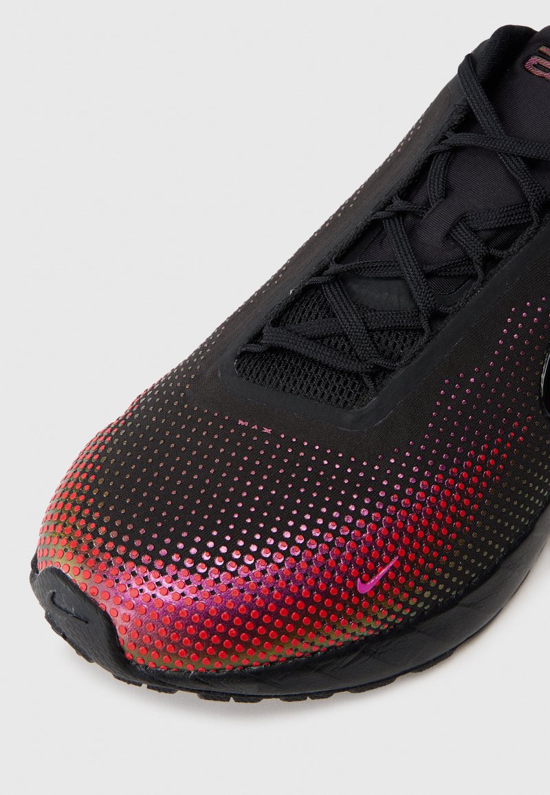 Zapatilla deportiva negra con un patrón degradado de pequeños puntos que van del rojo al púrpura, con una parte superior de malla y cordones negros.