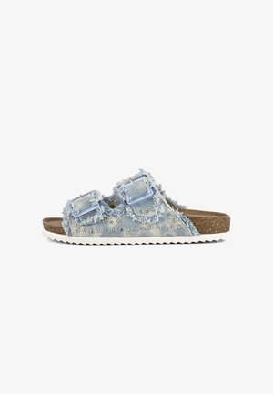 Sandales à glisser en denim bleu clair avec bords effilochés, doubles sangles réglables, clous métalliques et semelle en liège texturée. Semelle extérieure en caoutchouc blanc.
