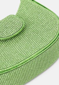 Borsa verde decorata con piccoli strass luccicanti, di forma arrotondata e con una base in tessuto testurizzato. Presenta una chiusura a patta e cuciture lisce.