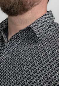 Kragen shirt in marineblauw met een geometrisch wit patroon, voorzien van een knoopsluiting en een gestructureerde stof. Accenten omvatten een scherpe kraag.
