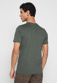 Olijfgroene katoenen T-shirt met een klassieke ronde hals, korte mouwen en een losse pasvorm, met een gladde textuur en zonder zichtbare afbeeldingen.