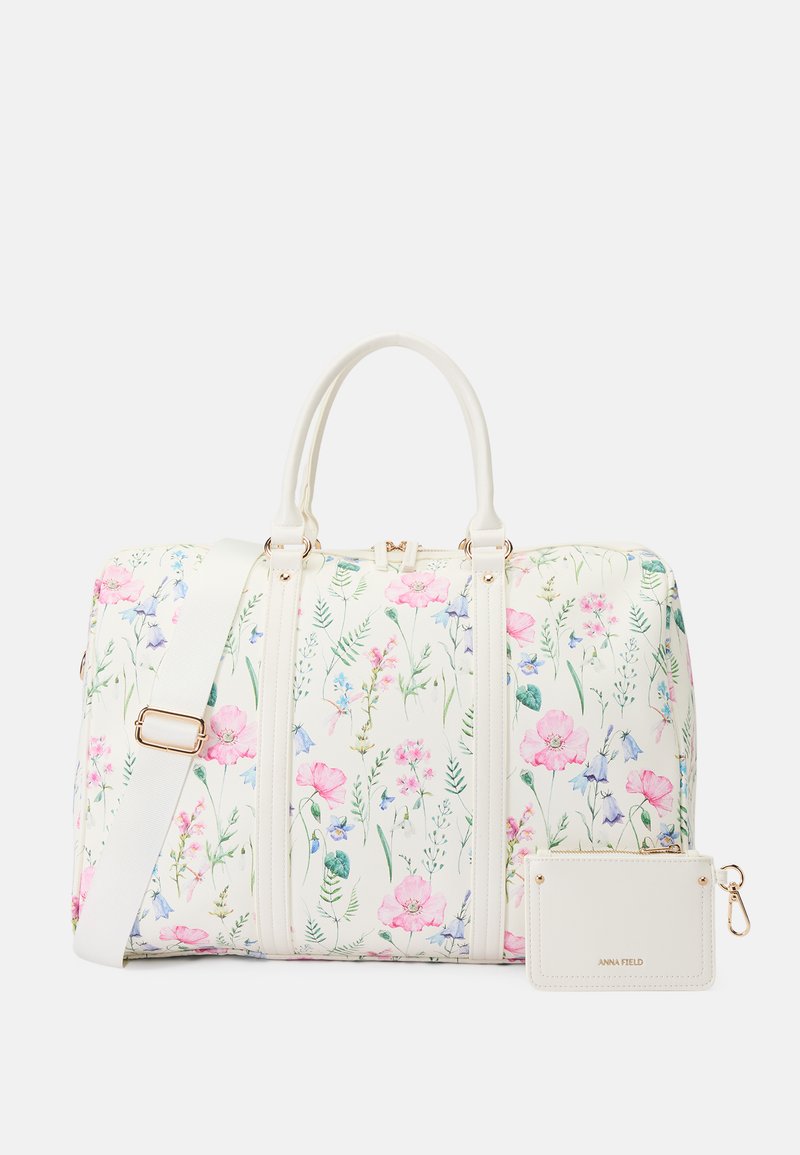 Duftesekk med blomstermønster på hvit bakgrunn, prydet med rosa og blå blomster, med doble hanke og en avtagbar liten kortholder med gullfarger.