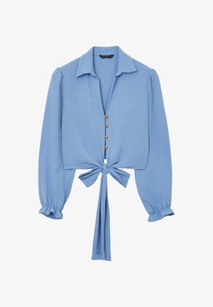 Bluse mit Knoten vorne aus hellblauem Stoff, mit langen Ärmeln mit elastischen Bündchen, Kragen und fünf Knopföffnungen vorne.