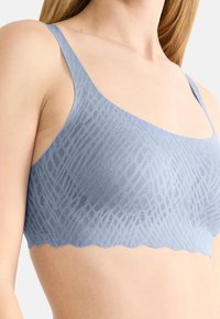 Svetlomodrá podprsenka s textúrovaným vzorom, nastaviteľnými ramienkami a zúbkovaným okrajom. Vyrobená z mäkkého, priedušného materiálu.