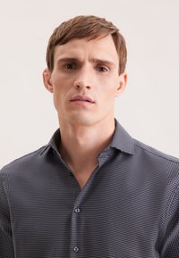 Camicia da uomo a quadri scuri con colletto button-down, motivo geometrico sottile e texture del tessuto liscia. Design minimalista senza loghi visibili.