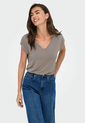 Camiseta gris con cuello en V y mangas cortas, combinada con jeans de mezclilla azul de cintura alta. Textura de tela suave con un ajuste relajado.