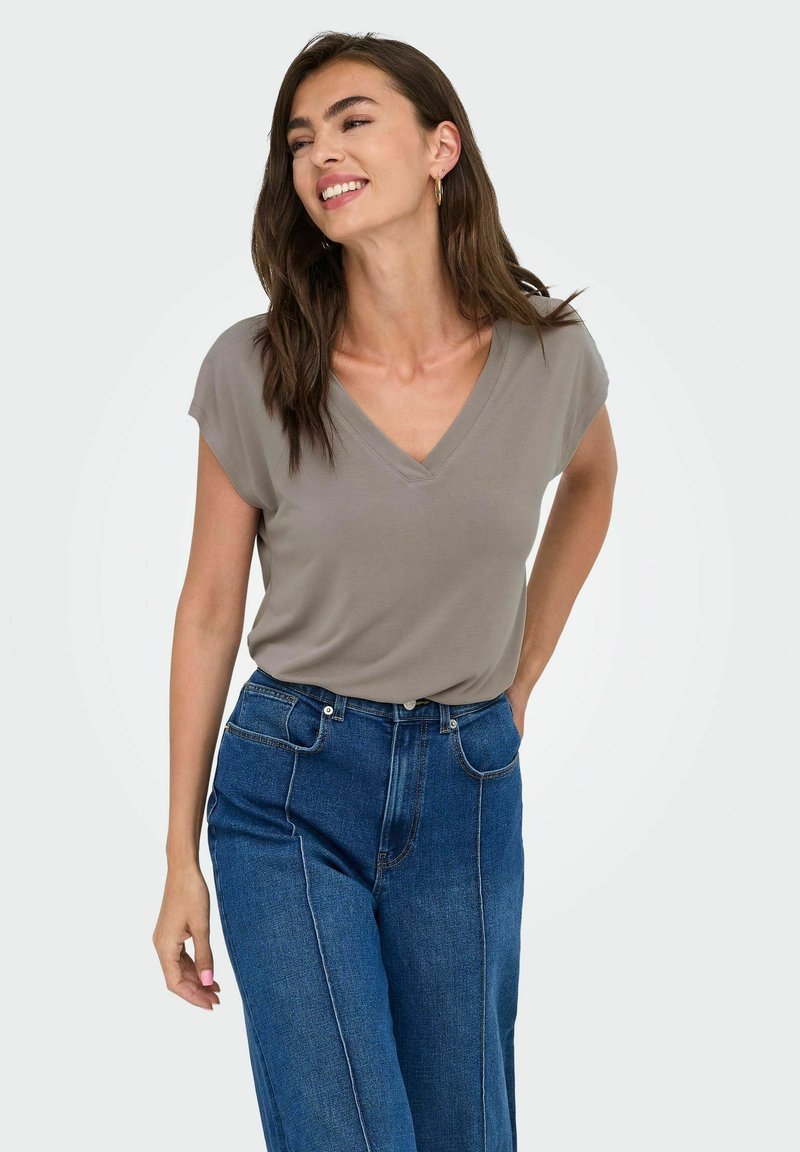 Camiseta gris con cuello en V y mangas cortas, combinada con jeans de mezclilla azul de cintura alta. Textura de tela suave con un ajuste relajado.