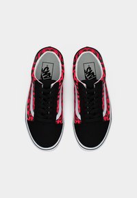 Ζευγάρι αθλητικών παπουτσιών Vans με μαύρες μύτες, πλευρές με κόκκινο και μαύρο λεοπάρ μοτίβο, λευκές λεπτομέρειες και μαύρα κορδόνια, που φαίνονται από πάνω σε λευκό φόντο.