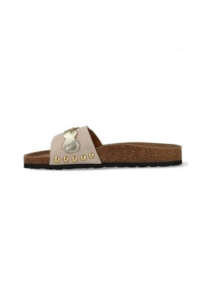 Beige suède slippers met kurken zool, zwarte loopzool, gouden metalen vlinderversiering en vijf gouden studs op het bandje.