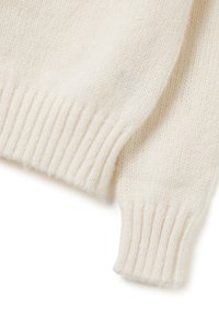 Suéter blanco de punto con dobladillo y puños acanalados, que presenta una textura suave y un corte holgado. La tela parece esponjosa y cálida.